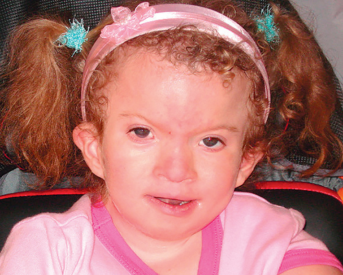 Nettie Faith Martz smiling, wearing a pink headband and turquoise butterfly hair clips.